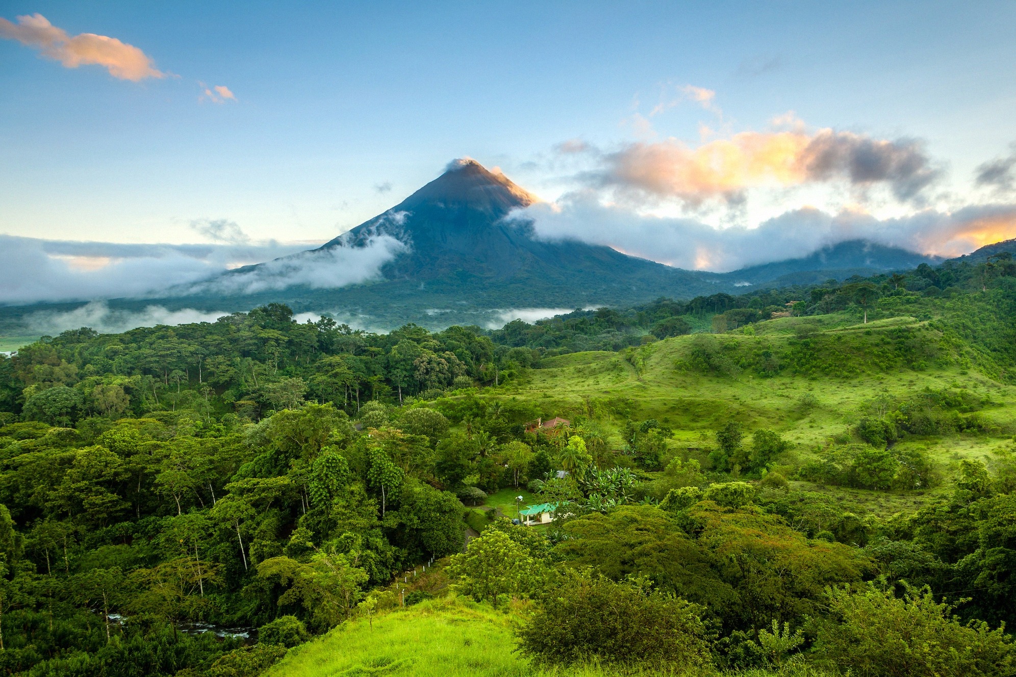 Arenal-tulivuori kohoaa auringonlaskussa trooppisen sademetsän yllä lähellä La Fortunaa, Costa Rica.