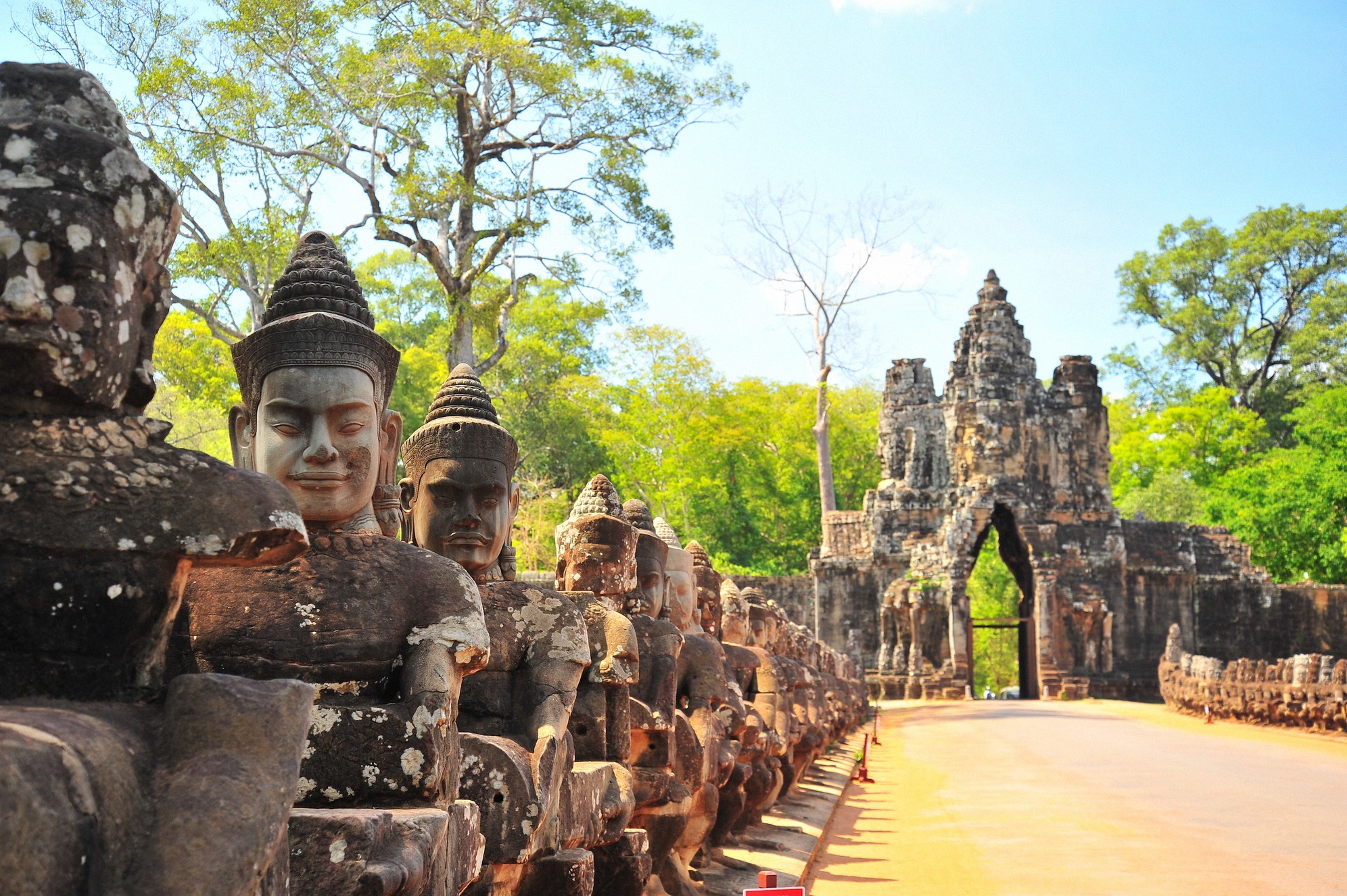 Angkor Thomin eteläportti pitkine kivisine jumalpatsasrivistöineen sillalla ja mahtava temppeliportti taustalla