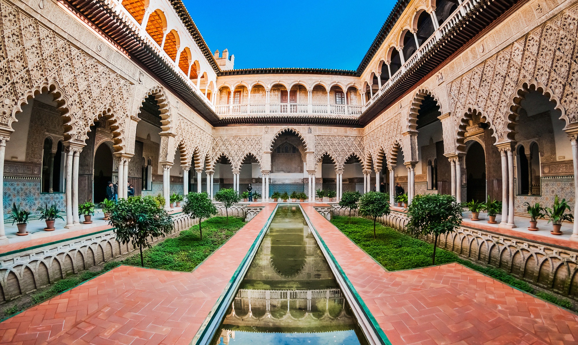 Patio de las Doncellas Sevillan Real Alcázarissa hevosenkenkäkaarineen, stukkokoristeluineen ja pitkine vesialtaineen.