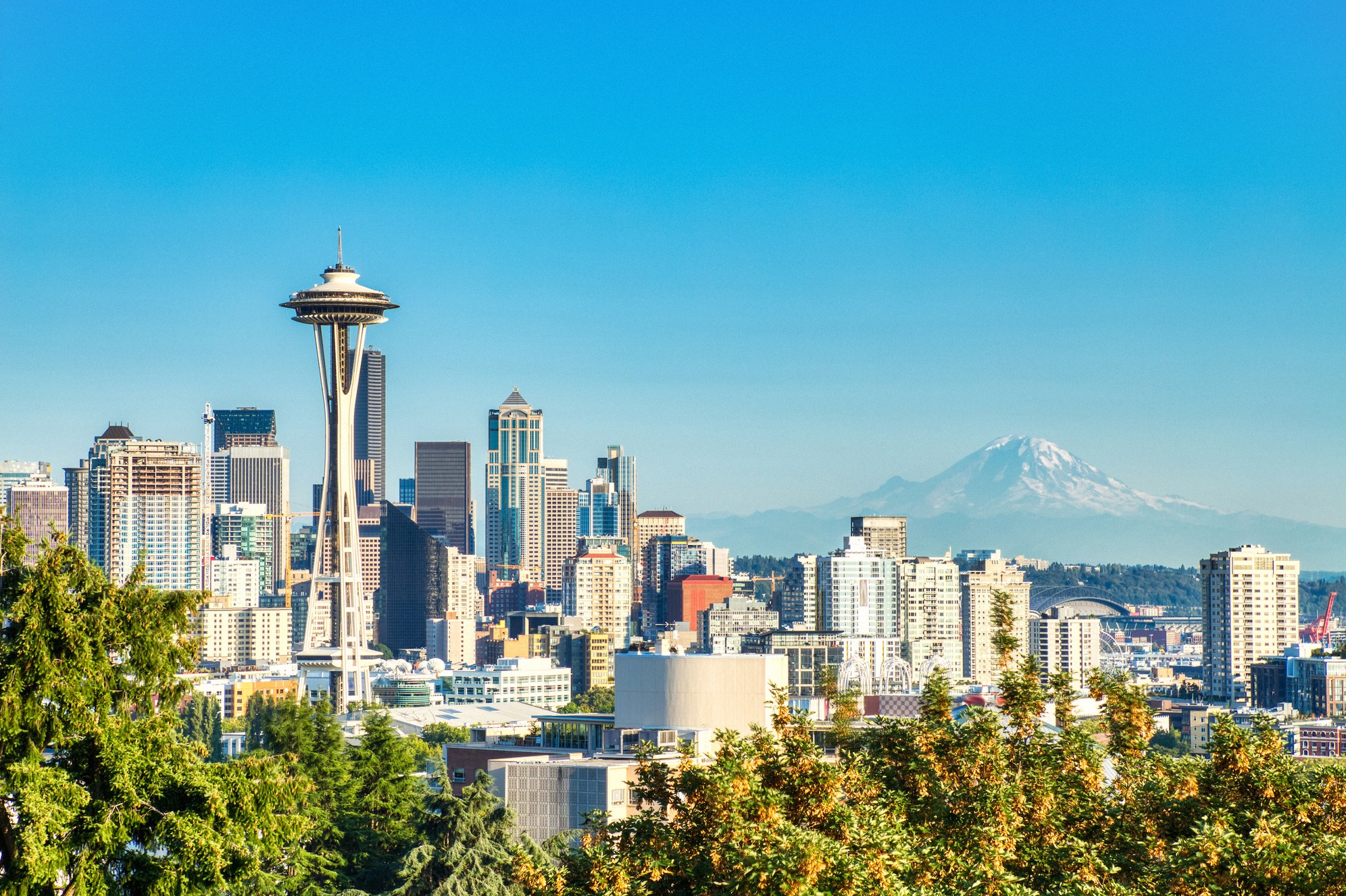 Seattlen silhuetti kirkkaana kesäpäivänä: etualalla tunnusomainen Space Needle ja horisontissa lumipeitteinen Mount Rainier.