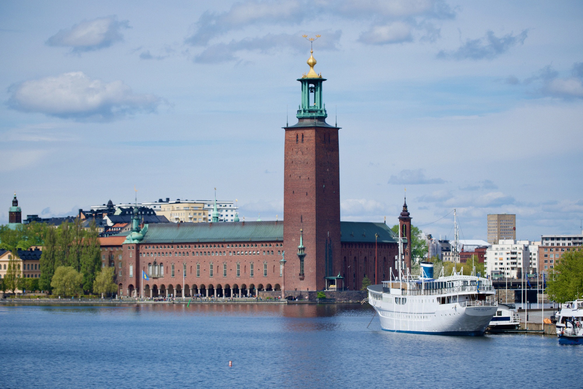 Tukholman kaupungintalo (Stadshuset) tunnusomaisine tiilitorneineen ja kultaisine kruunuineen kuvattuna Mälarenilta.
