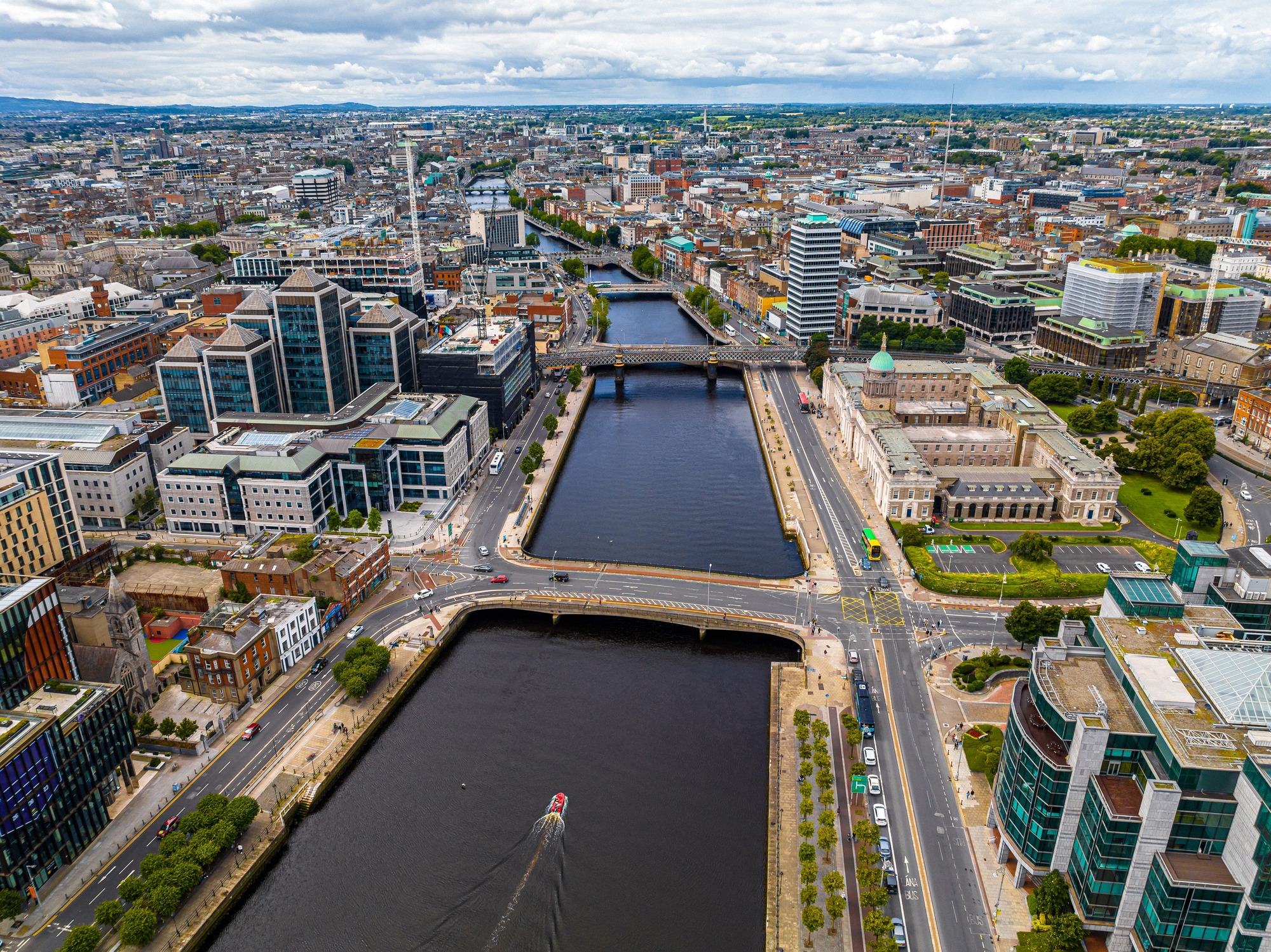 Valkoiseksi maalattu valurautainen Ha'penny Bridge Liffeyn yli jalankulkijoineen kirkkaan sinisen taivaan alla.