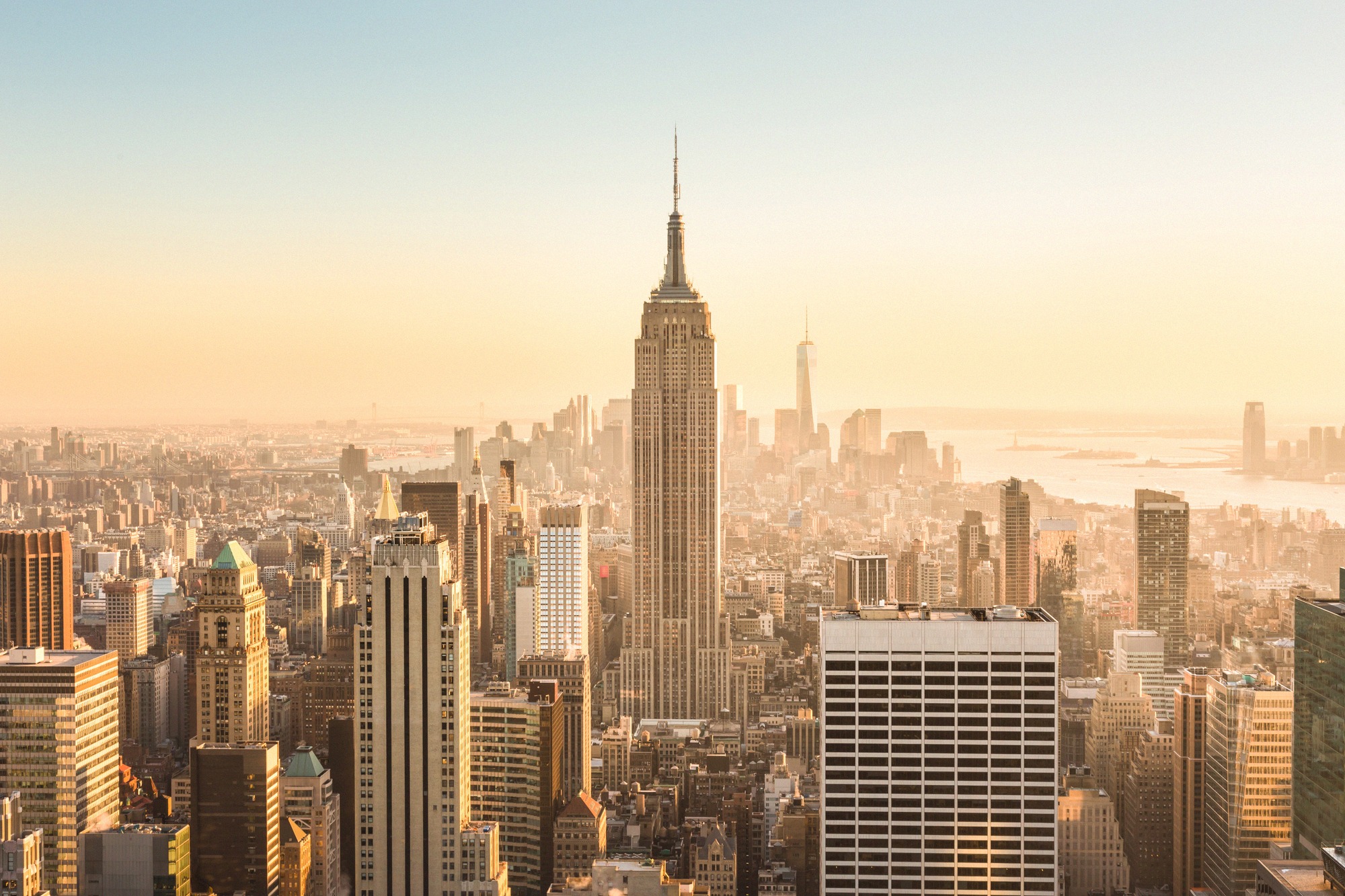 Empire State Building kohoaa Midtown Manhattanin pilvenpiirtäjien yllä kultaisessa iltavalossa.