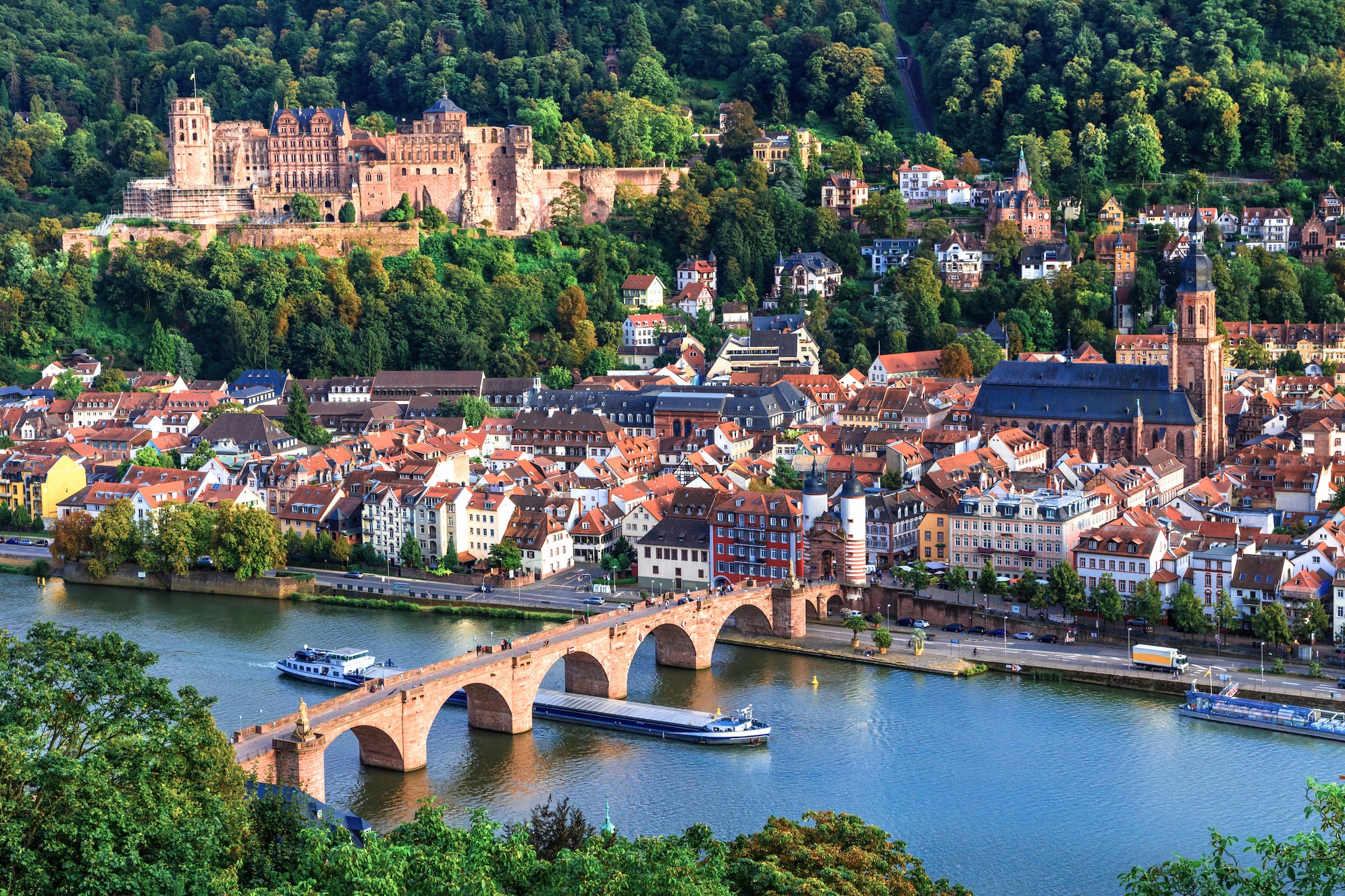 Klassinen näkymä Heidelbergiin: punainen linna metsäisellä rinteellä, historiallinen Vanha silta (Karl-Theodor-Brücke) Neckarin yli ja vanhankaupungin katot, yksi Saksan valokuvatuimmista panoraamoista.