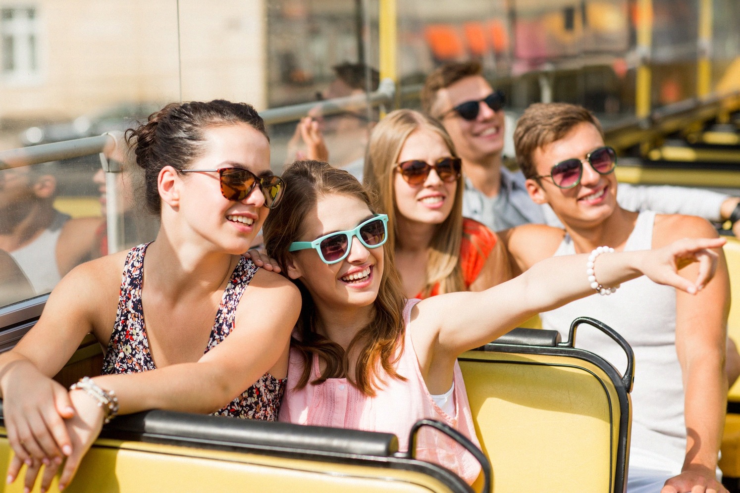 Nuoria matkailijoita hop on hop off -kiertoajelubussin avoimella yläkannella.