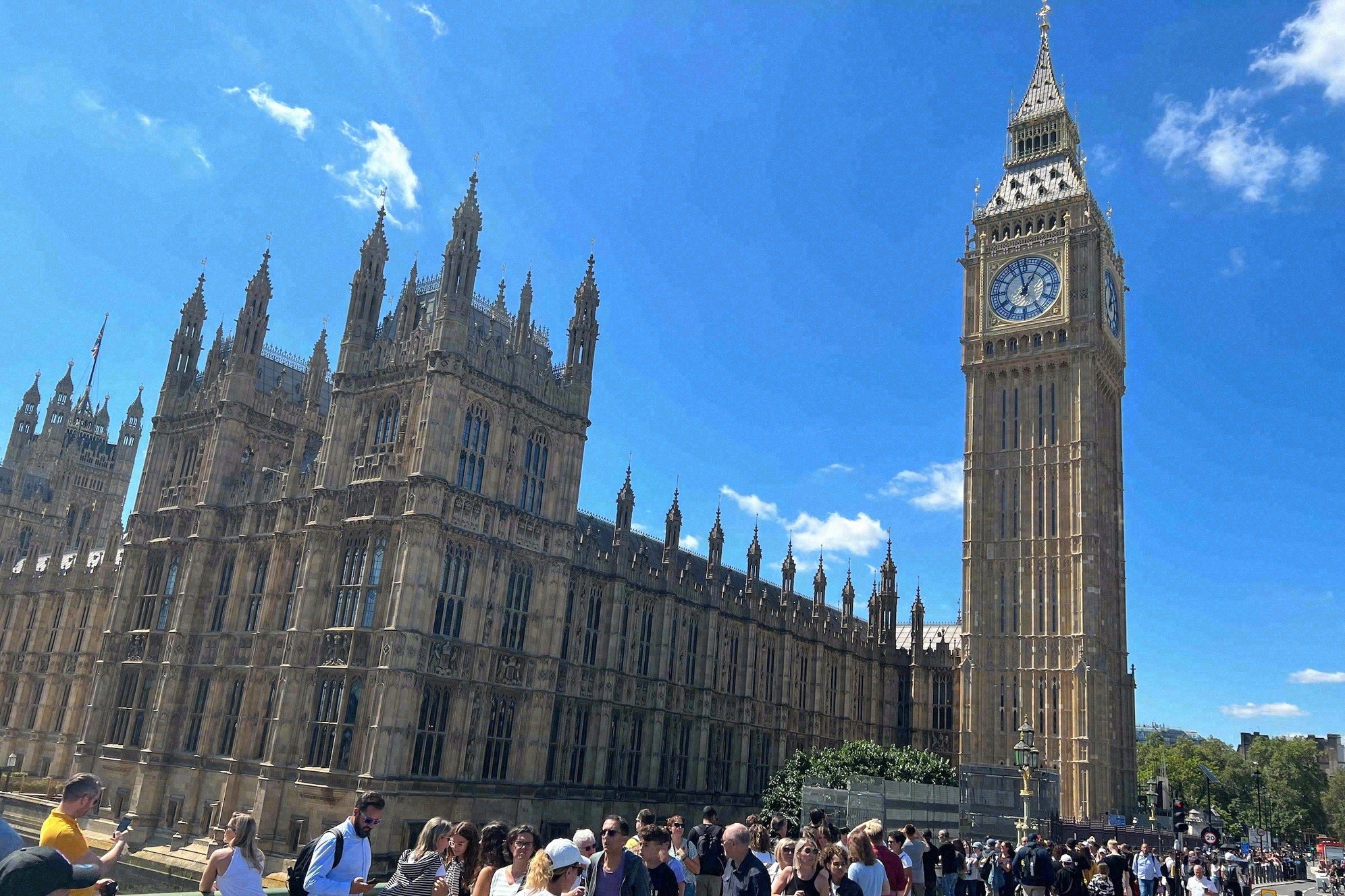 Big Ben ja Westminsterin palatsi Parliament Streetiltä kuvattuna, etualalla punainen kaksikerroksinen bussi, oikealla moderni toimistorakennus.