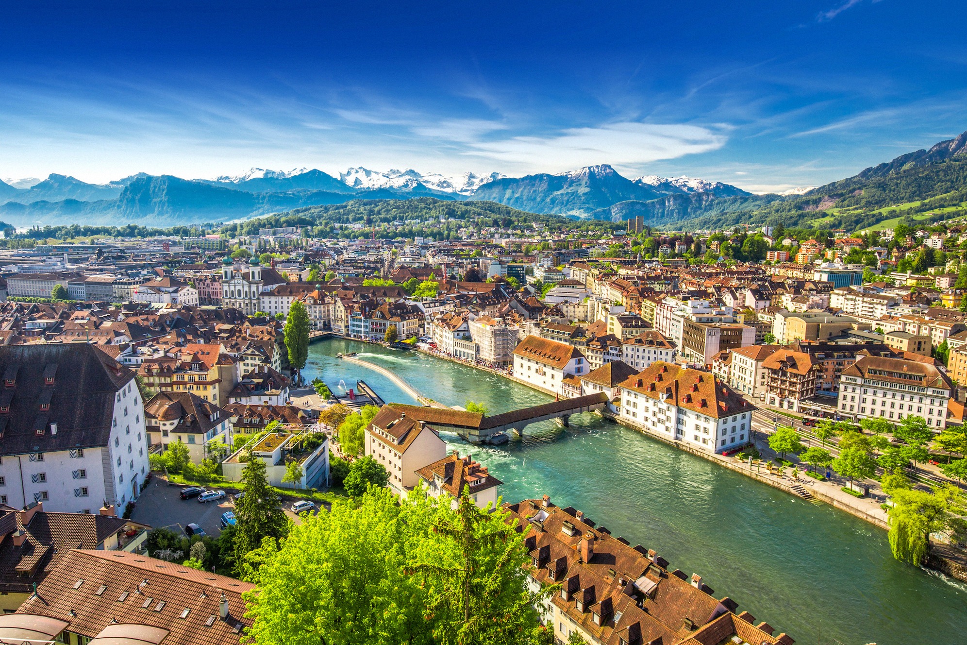 Ilmava kaupunkipanoraama Luzernista, jossa Reuss-joki, vanhankaupungin historialliset sillat ja lumihuippuinen Pilatus taustalla.