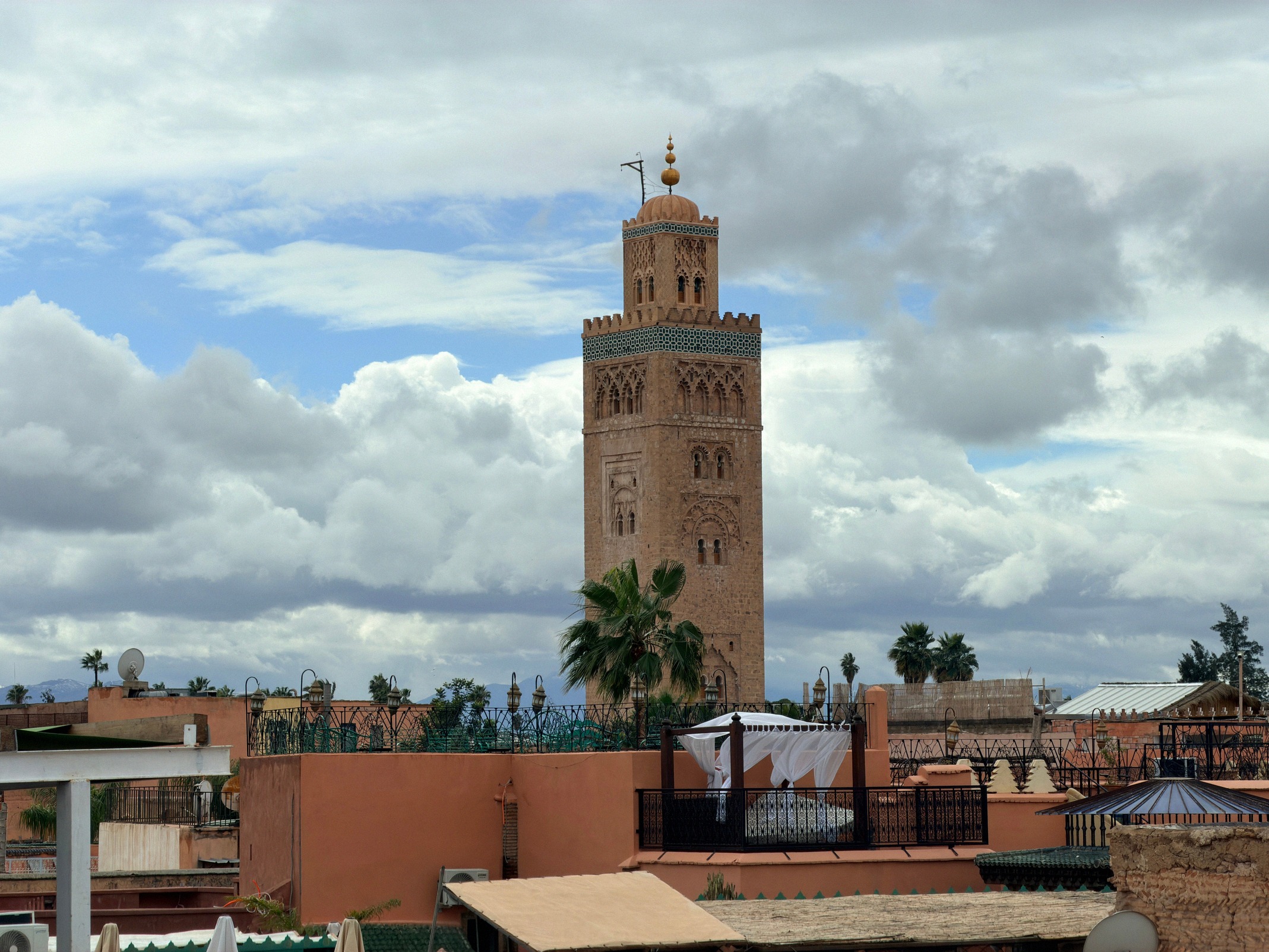 Näkymä kattoterassilta Koutoubian moskeijan solakkaan minareettiin, Marrakechin maamerkkiin, pilvisen taivaan edessä