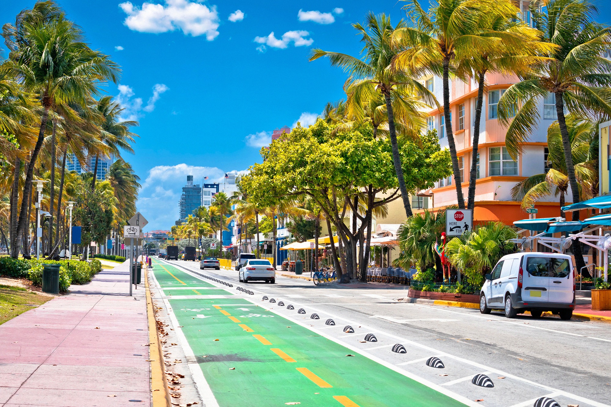 Ocean Drive Miami Beachillä pastellinsävyisine art déco -julkisivuineen, palmuineen ja vihreäksi merkittyine pyöräteineen.