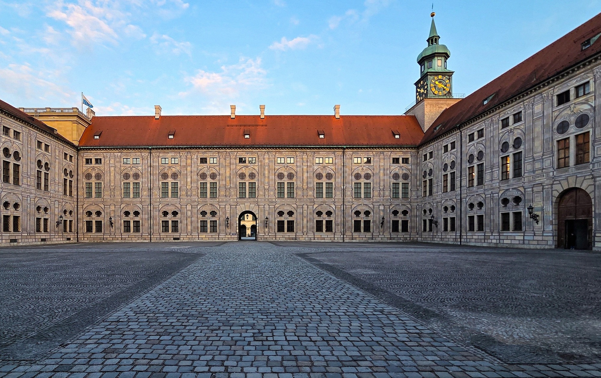 Münchenin residenssin kivetty sisäpiha renessanssijulkisivuineen ja kellotorneineen aamuvalossa.