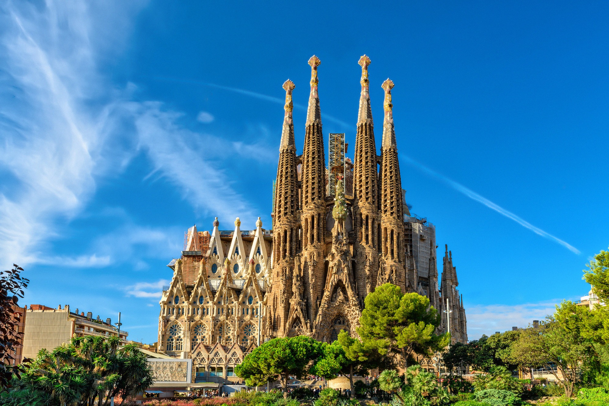 Näkymä Sagrada Famílian upealle syntymäjulkisivulle Barcelonassa, tunnusomaiset hienosti koristellut tornit kirkkaan sinistä taivasta vasten.