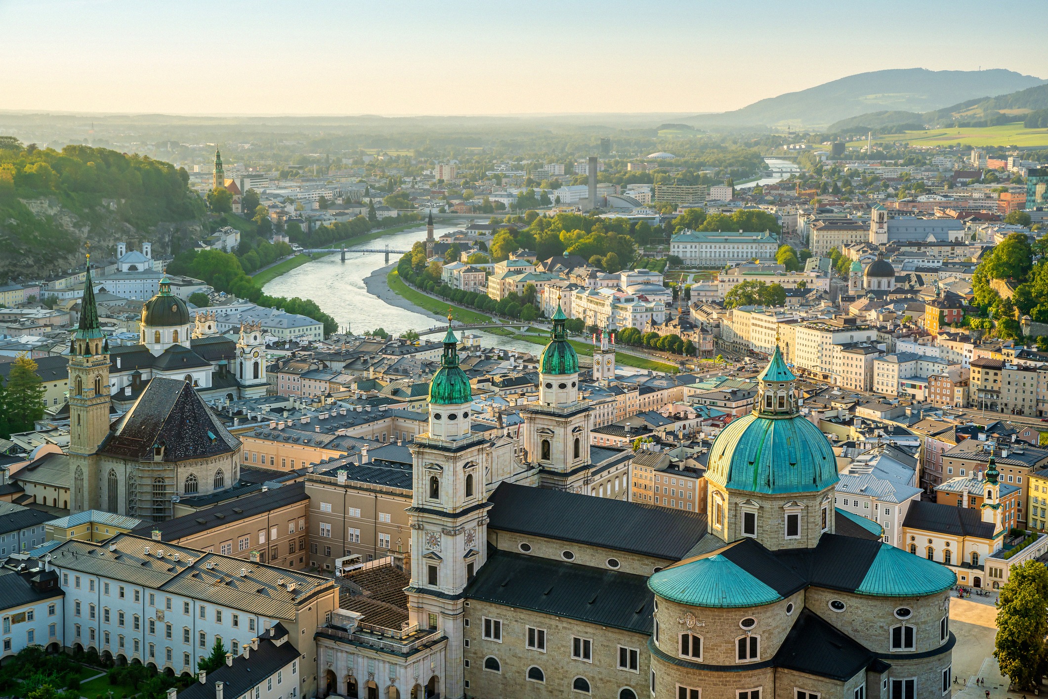 Näkymä Salzburgin vanhaankaupunkiin aamuvalossa, mukana tuomiokirkko, Salzach-joki ja Alpit.