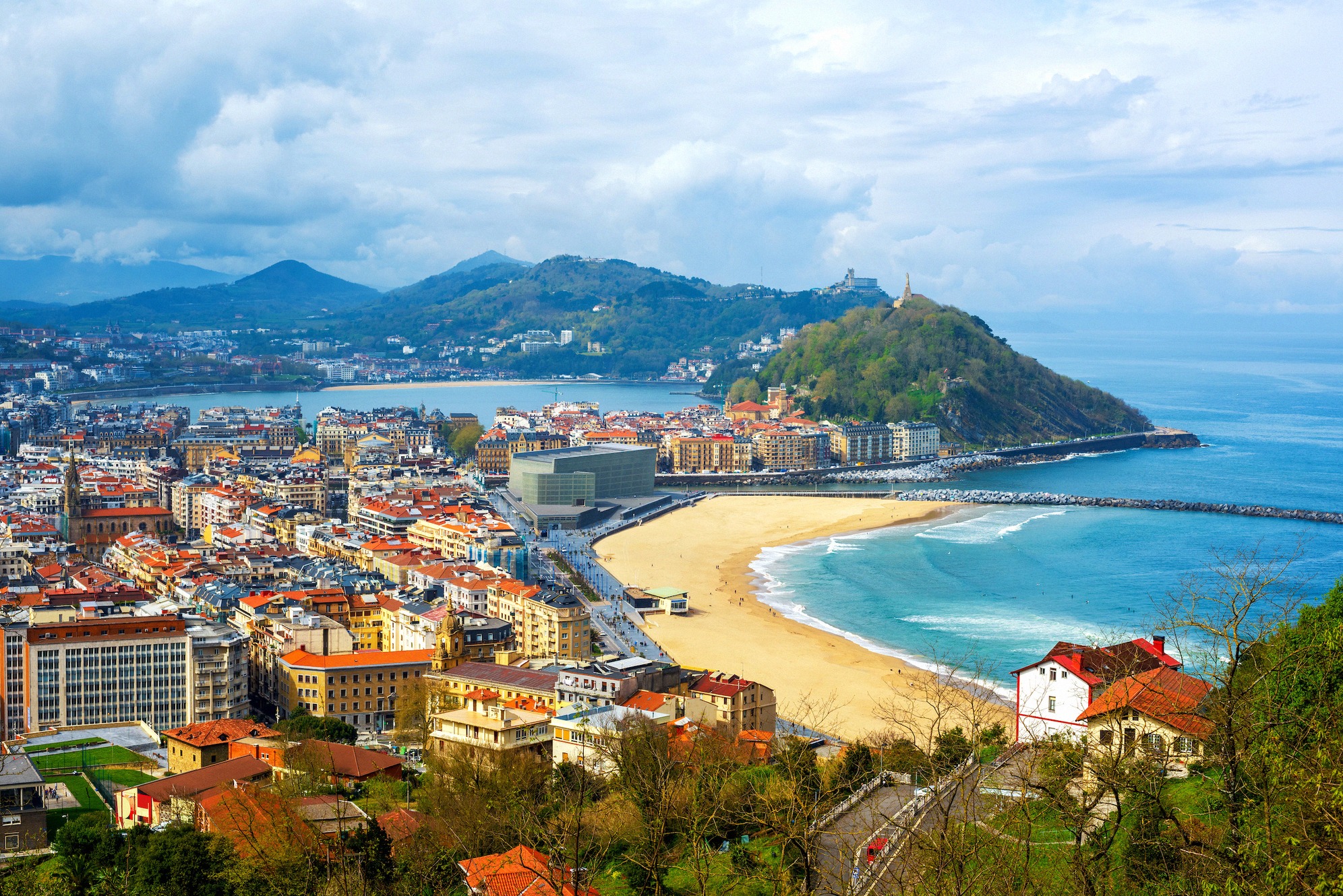 Panoraamanäkymä San Sebastiánin (Donostian) yli Baskimaassa Espanjassa: kaartuva Playa de la Concha kultaisine hiekkoineen ja tunnusomainen Monte Urgull -kukkula ovat tyylikkään rannikkokaupungin maamerkkejä.