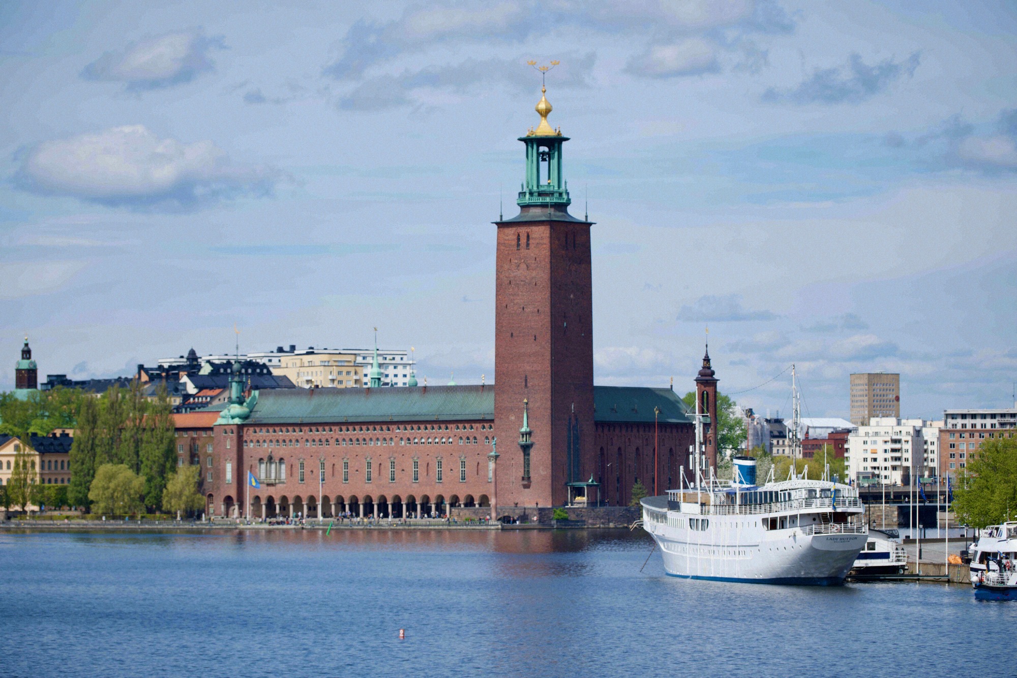 Tukholman kaupungintalo (Stadshuset) tunnusomaisine tiilitorneineen ja kultaisine kruunuineen kuvattuna Mälarenilta.