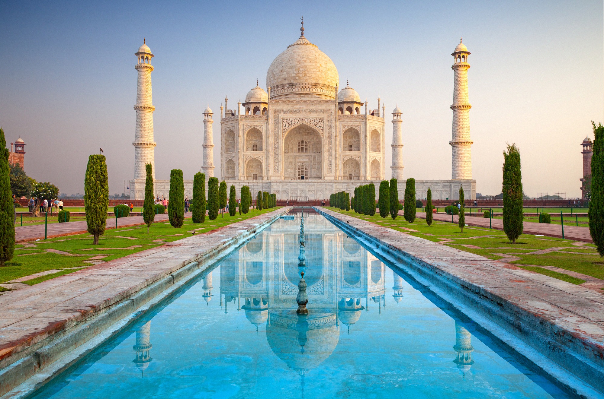 Agran Taj Mahal pitkän vesialtaan takana, marmorikupoli ja minareetit heijastuvat aamuvalossa.