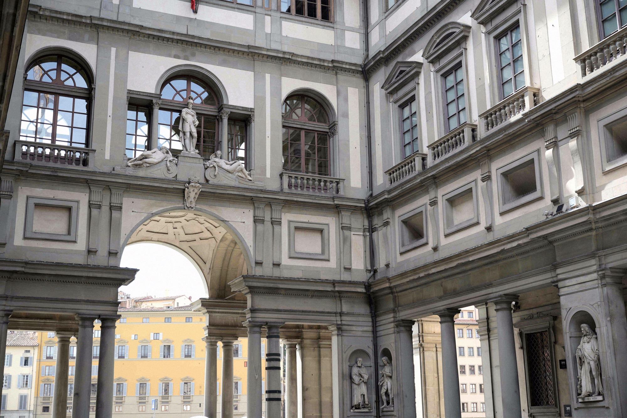 Uffizin sisäpiha gallerian julkisivun elegantteine pylväskaarineen ja näkymä holvikäytävän läpi vastapäisiin renessanssitaloihin.